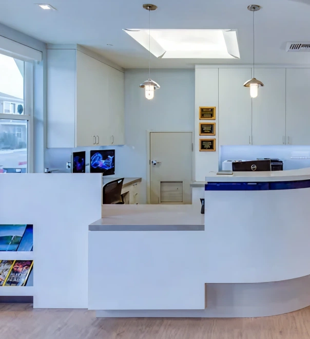 Modern dental office reception area with white curved desk and clean interior design.