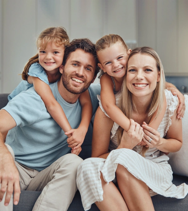 Happy family of four smiling together indoors on comfortable seating