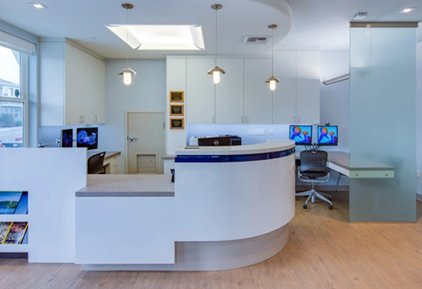 Modern dental office reception area with curved white desk and contemporary design elements.