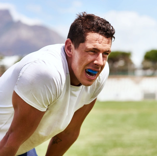 Man in white shirt stretching outdoors on grass field during daytime.