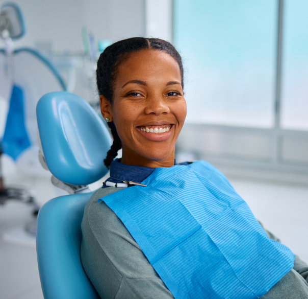 Smiling woman in dental chair wearing blue bib in modern dental office