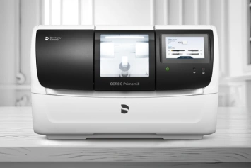 Modern dental laboratory analyzer machine with three display screens on white countertop in clinical setting.