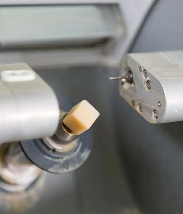 Close-up of dental handpiece with bur attachment and suction device in clinical setting.